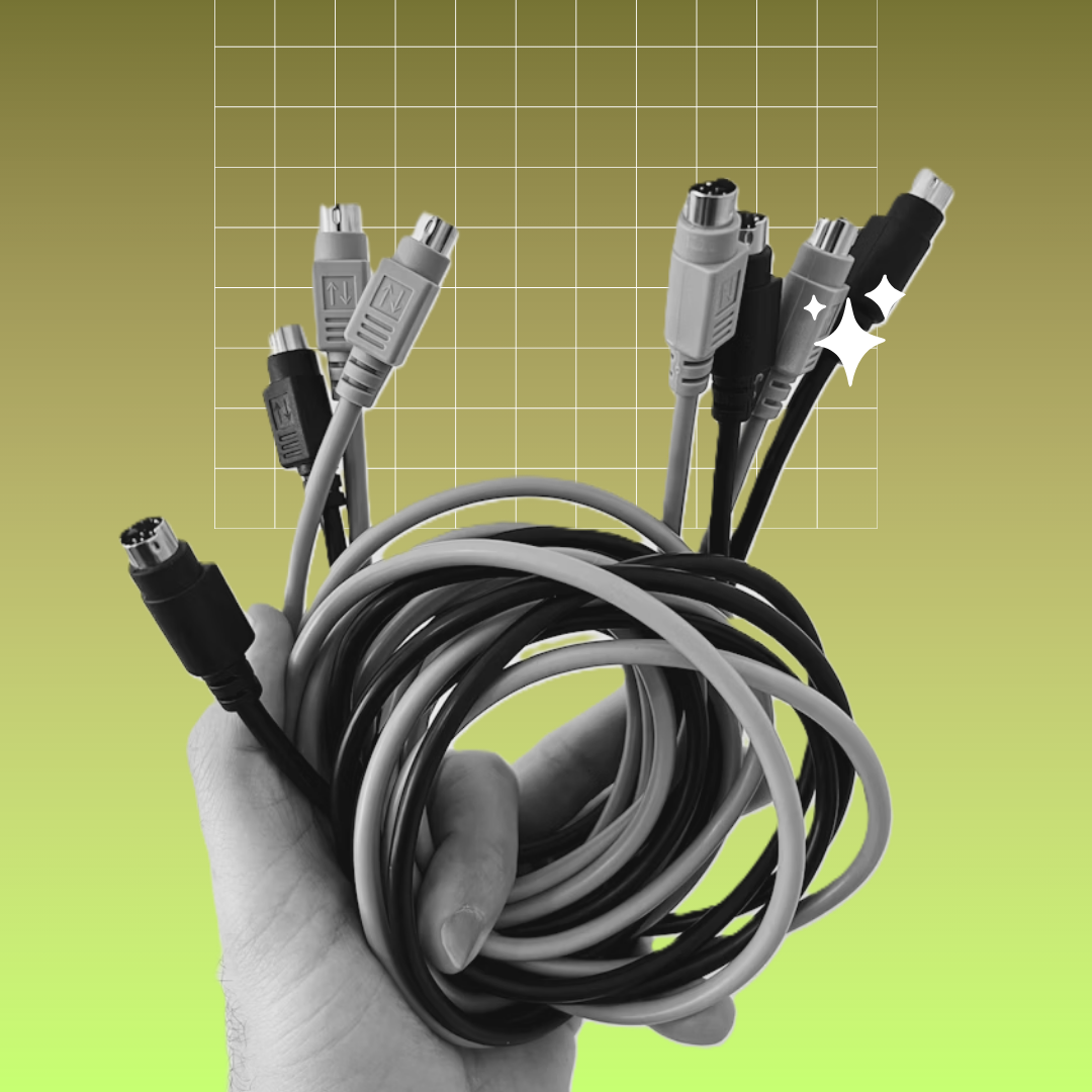 A person's hand holding cables of various sizes and colors, wrapped in a coil. They are isolated in a bright green background.